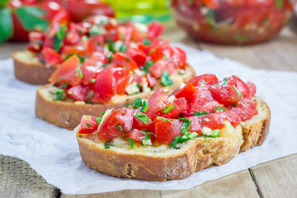 Hrianku potrite cesnakom, polejte olivovým olejom a uložte na ňu paradajky. Foto: Shutterstock
