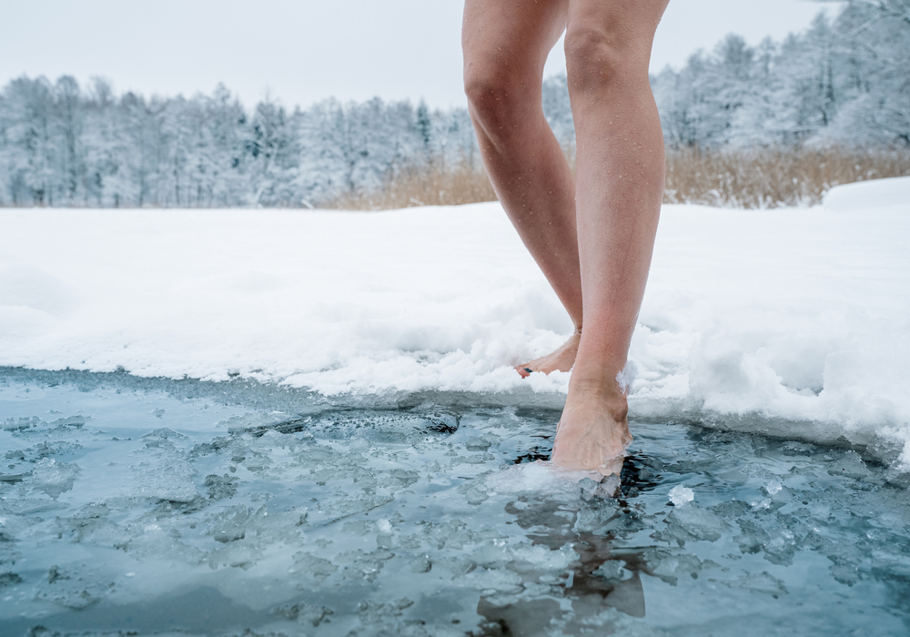 Žena vstupuje do zimného jazera, otužovanie.
