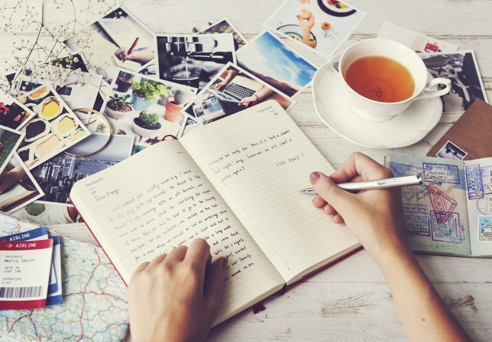 Rozpísaný denník, na stole fotky a šálka čaju.