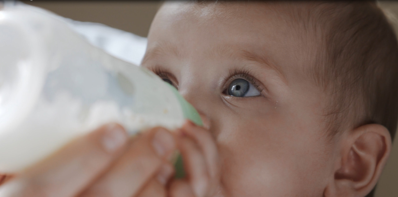 Dieťa, ktoré pije mlieko z fľašky